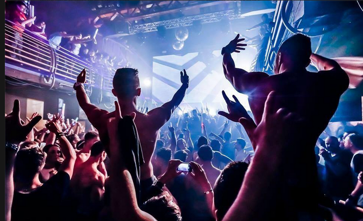 Shirtless men indulge in the euphoria associated with electronic dance music and strobe lights.