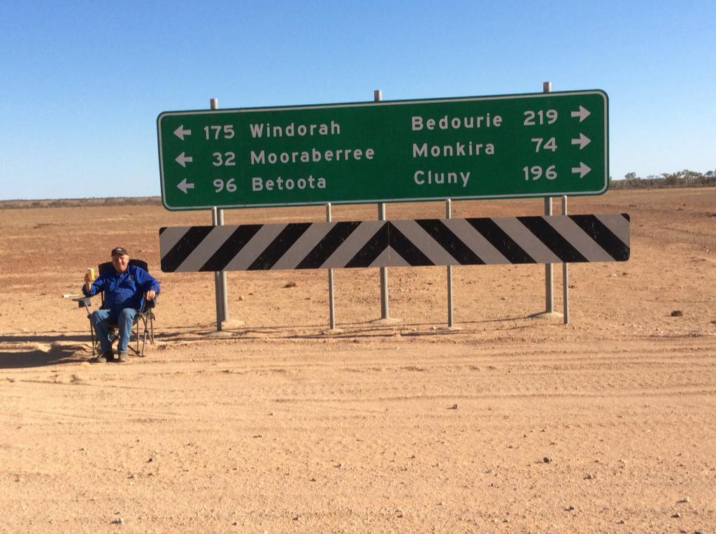 Tony Windsor poses next to a road sign, 96 kilometres from Betoota